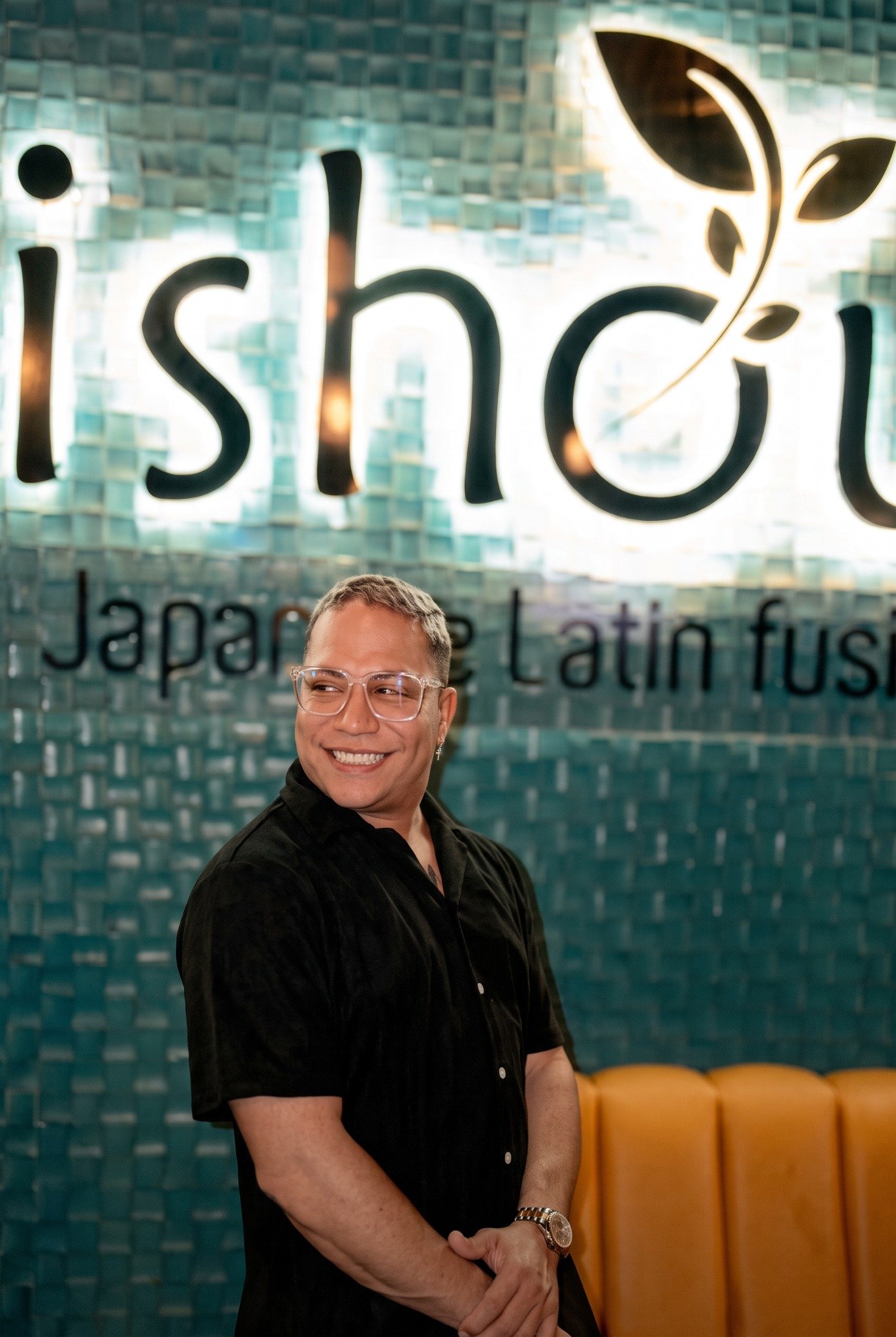 Invitado de Mishou frente al logo del restaurante